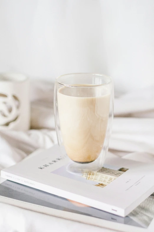 a glass and book sitting on a bed