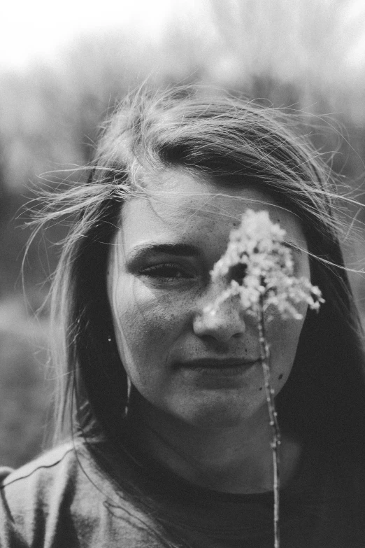 the  is holding her flowers up to her face