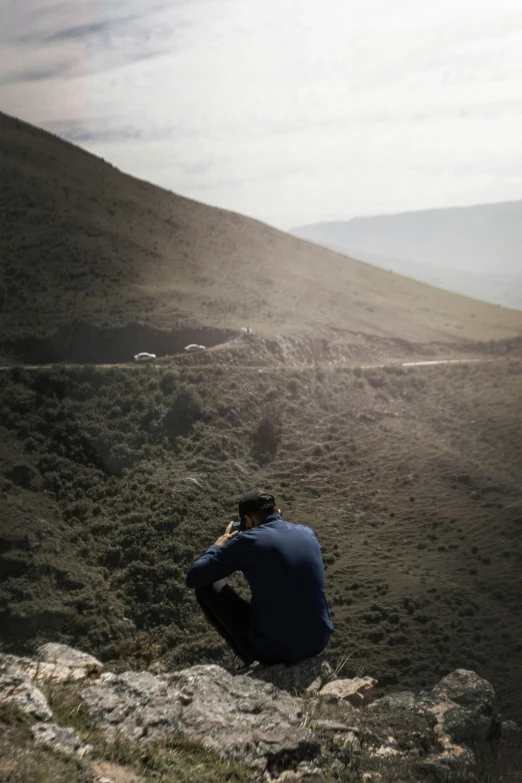 a man sitting on top of a hill with a camera