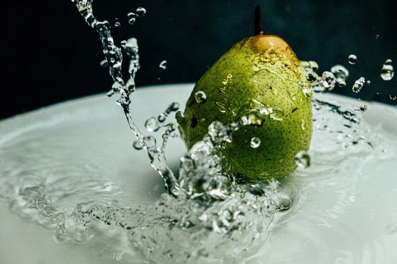 there is a green pear splashing in the water