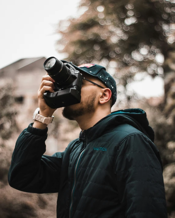 a man with black jacket and cap holding a camera