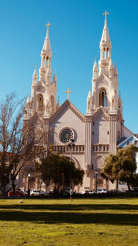 an older cathedral stands on the grassy side of a city park