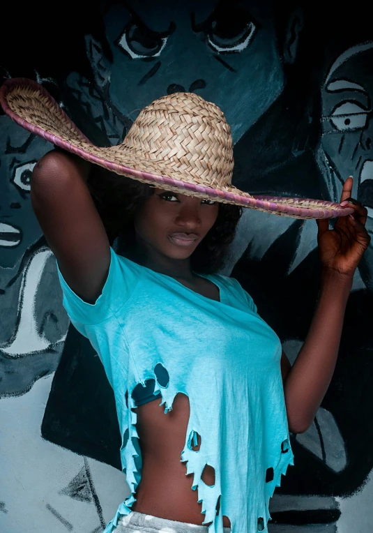 a woman wearing a straw hat and standing in front of wall