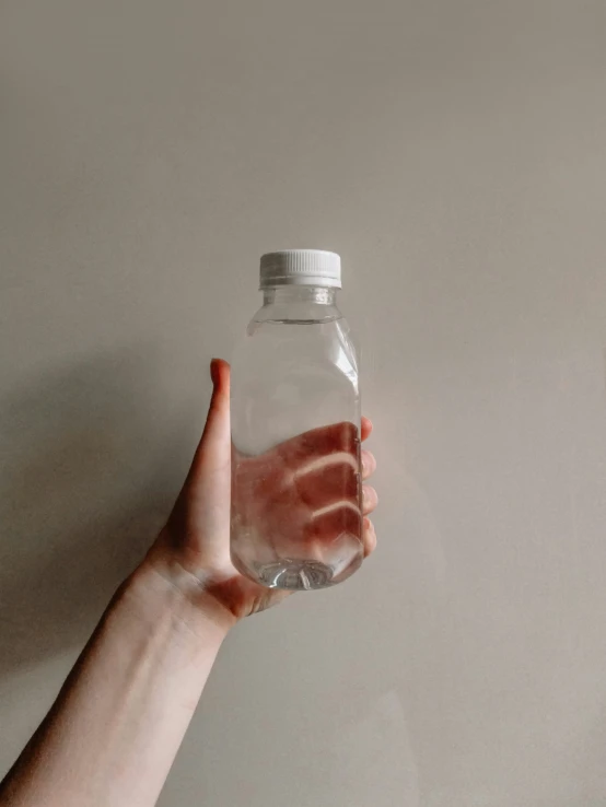 a hand holding a water bottle with it's cap open