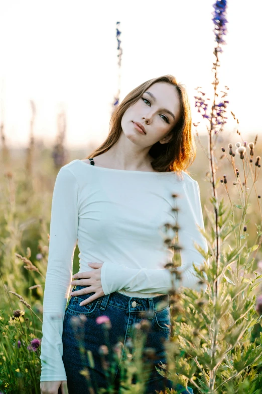 a woman standing in some tall grass with her hands on her hips