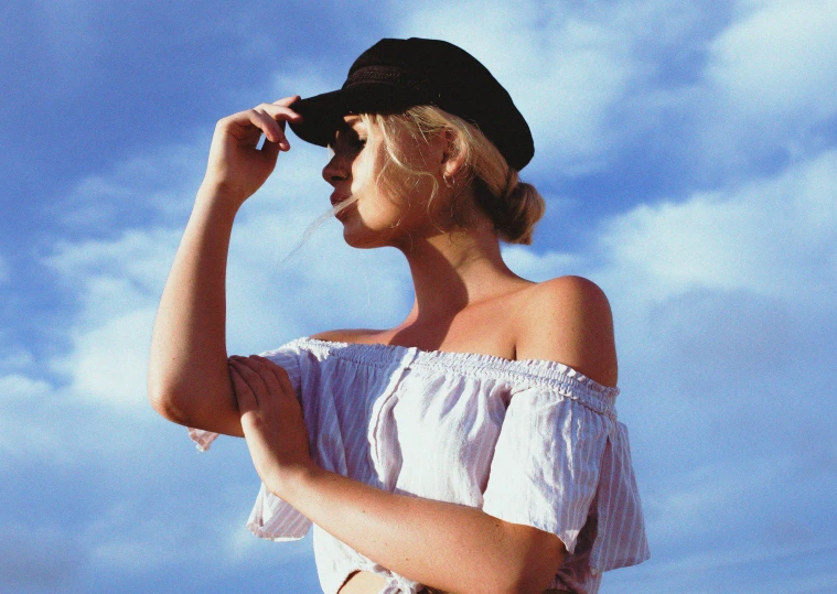 a woman in white off the shoulder shirt and hat posing for a picture