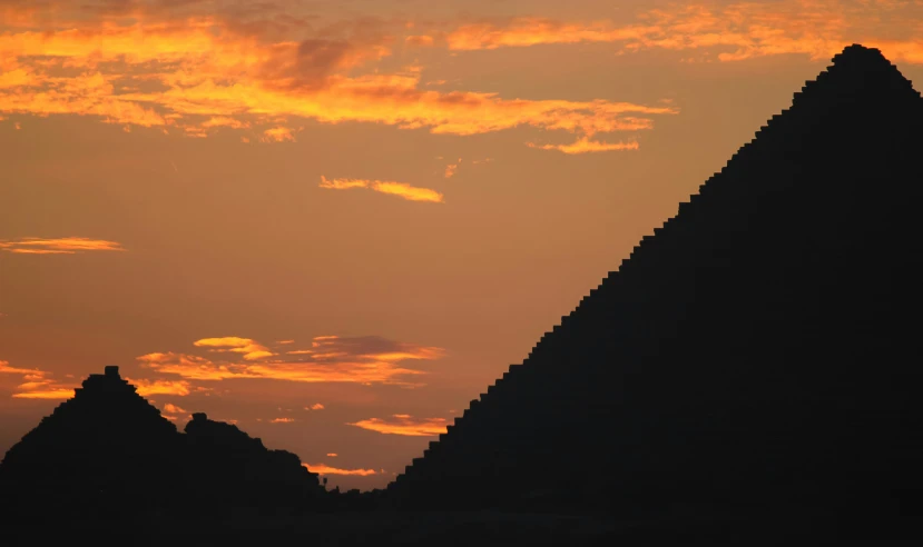 the sun sets behind three large pyramids