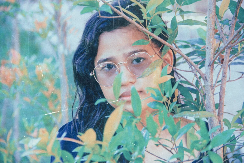 an oil painting of a girl peeking out from the leaves