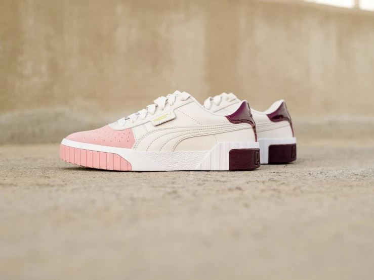 a white, pink and purple sneaker on a sidewalk