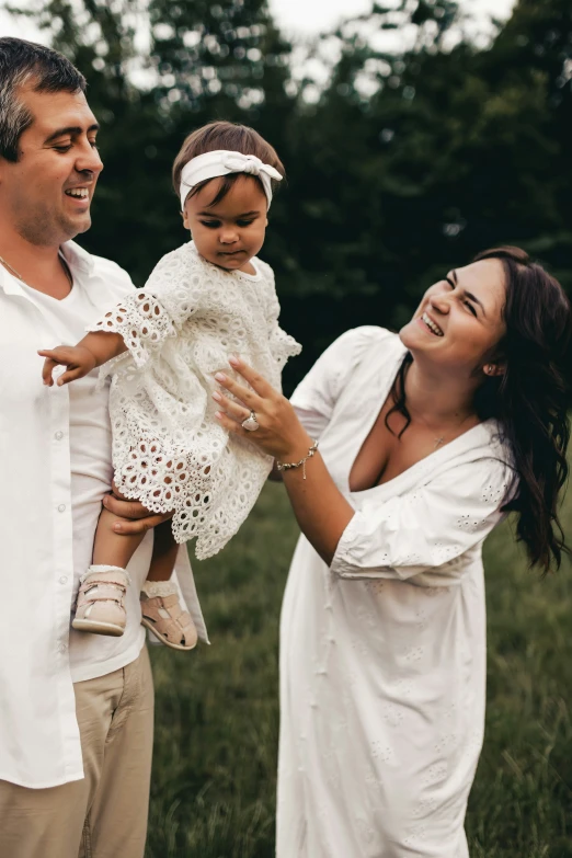 a woman holds the arms of her man while holding his baby