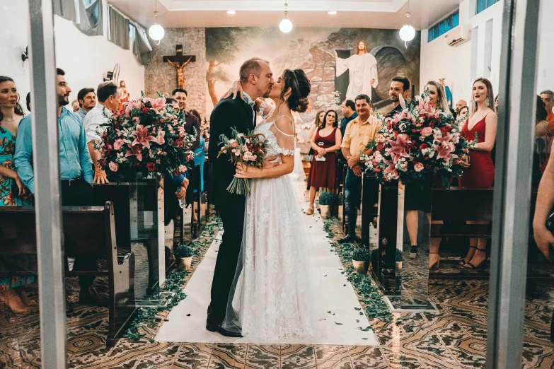 a bride and groom kissing in the aisle of a church