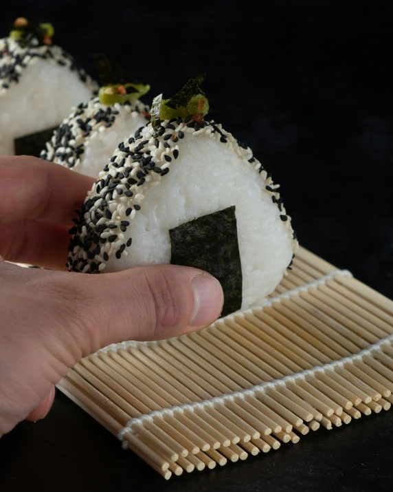 a close up of a person taking sushi from a bamboo tray