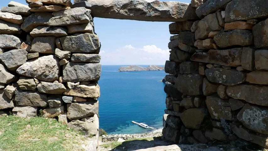 a stone wall overlooks the water and a boat on a body of water