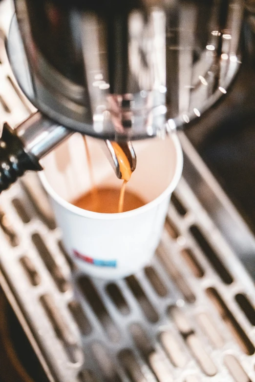 a person pouring soing into a cup from an espresso