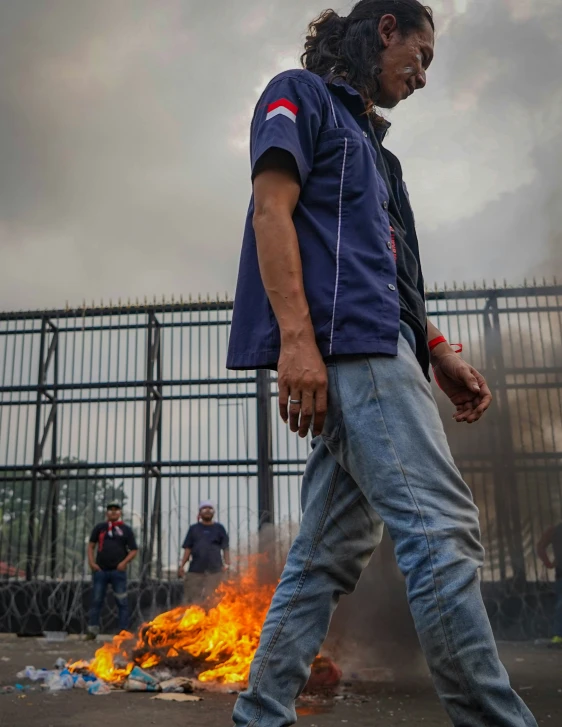 a man walking past fire and smoking cigarette