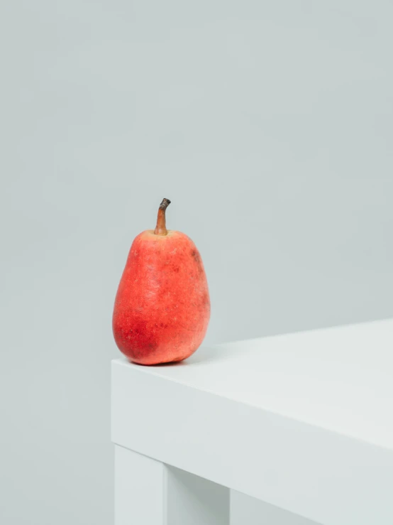 an apple sitting on a white table in front of a light gray background