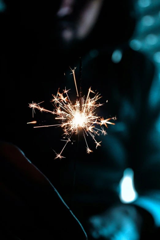someone holding a sparkler in their hand, lit up