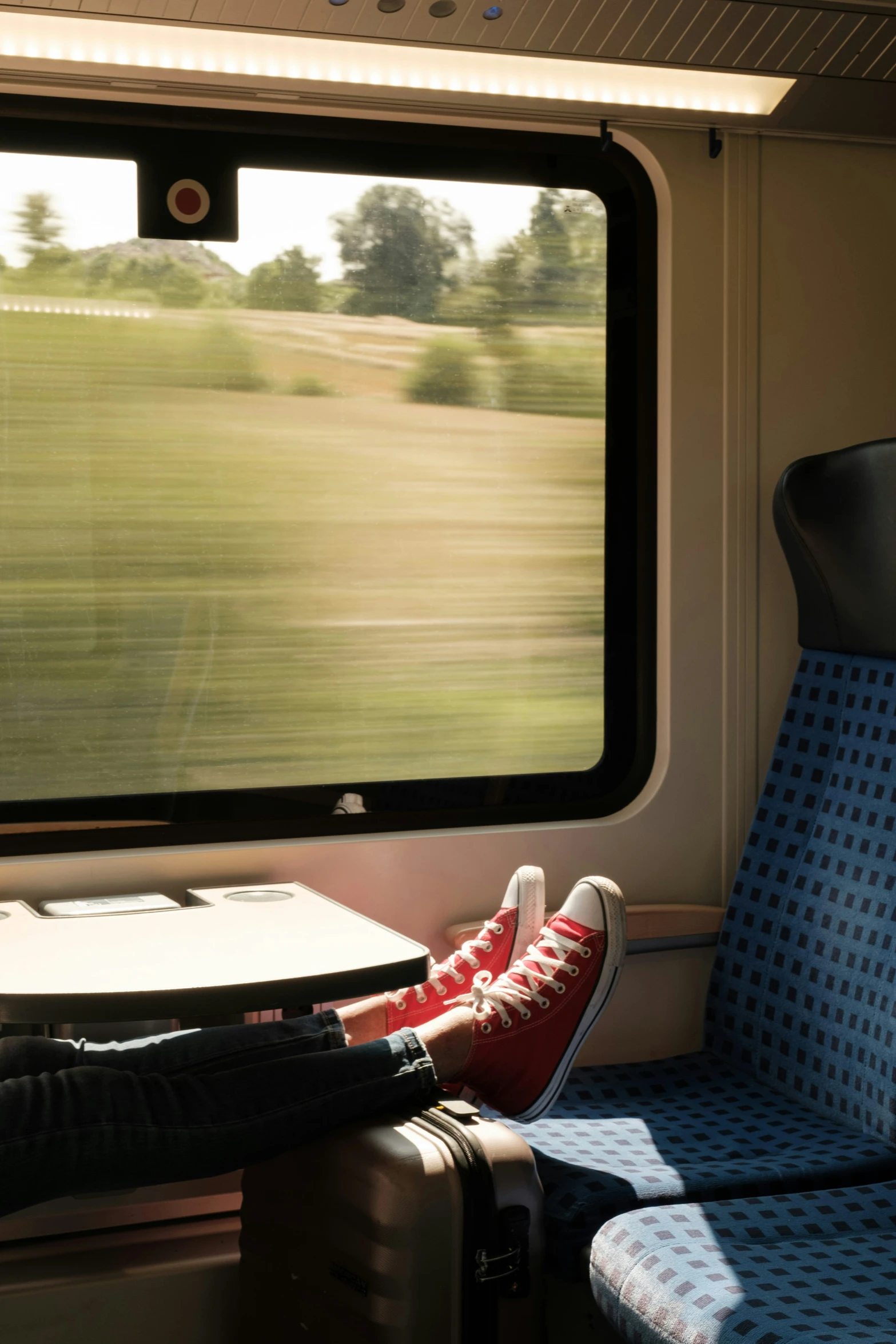 a pair of feet with their red converses resting in the front of a train