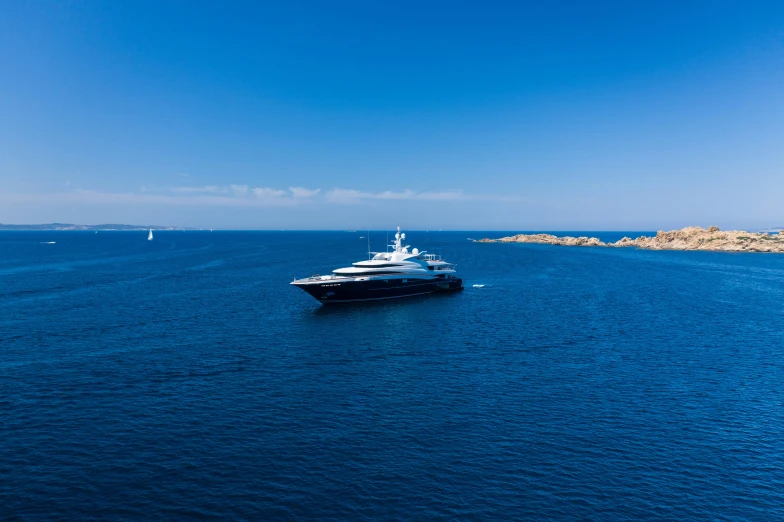 large boat sailing in open ocean with sailboat in the background