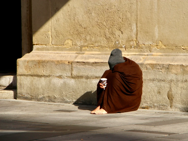 a man with a hat is sitting down eating coffee