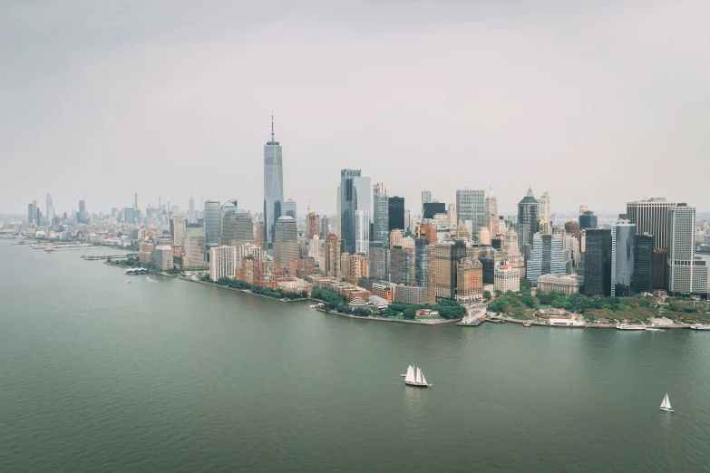 sailboats float past the city's skyline as a boat is seen in the river