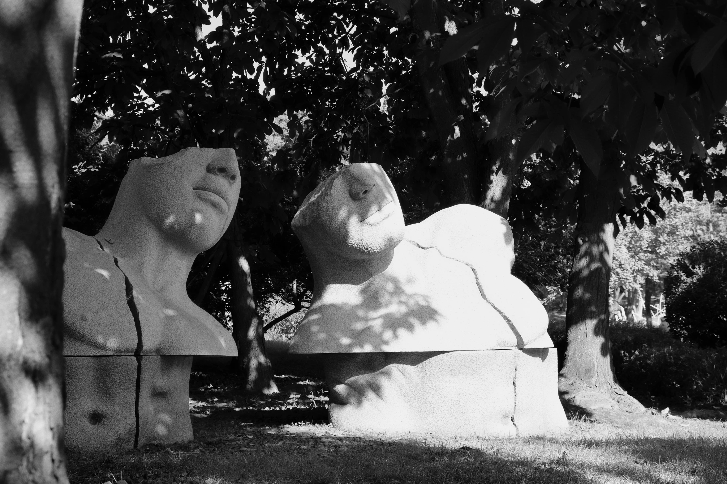 black and white pograph of two large statues with trees in the background