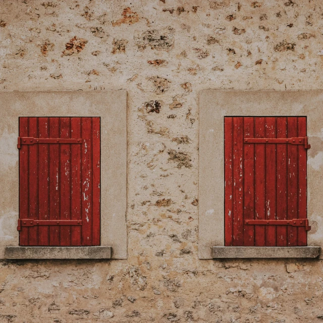 two red shuttered windows in a adobe building