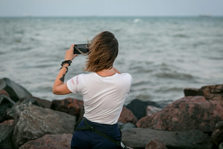 a man taking a po by the ocean with his cell phone