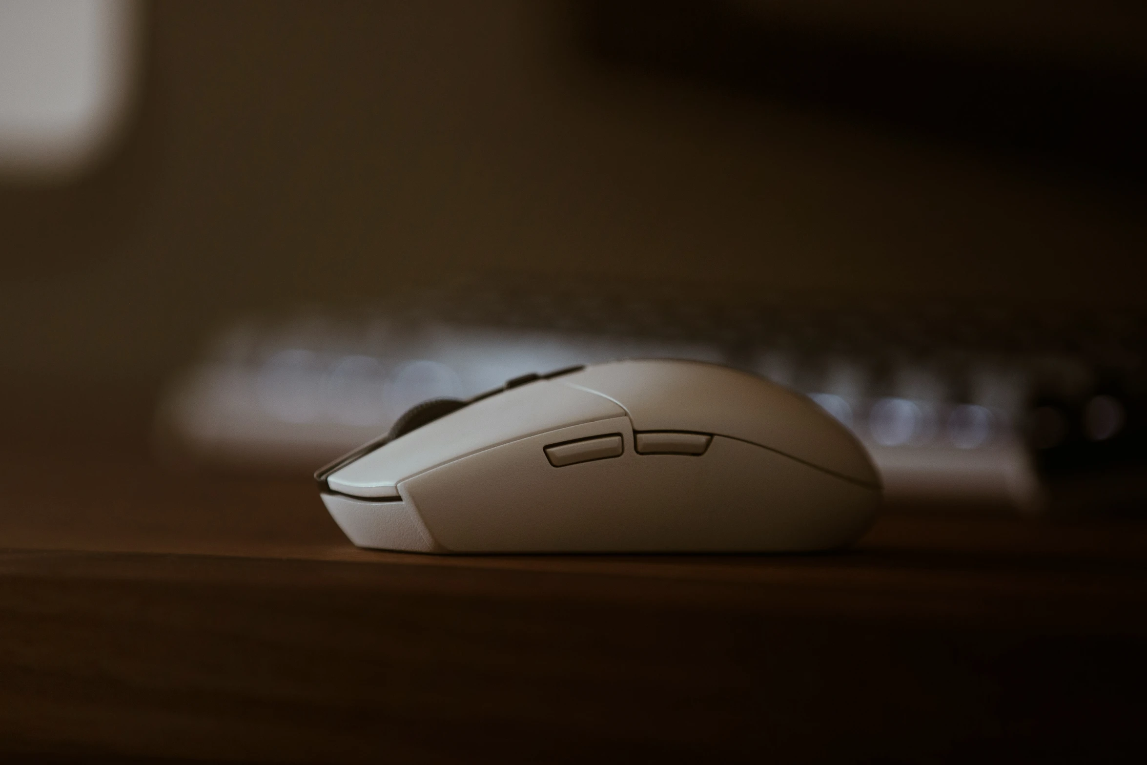 a mouse sits on the table near a keyboard