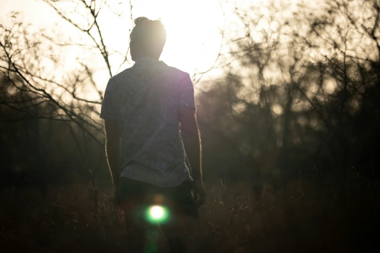 a person standing in the grass under a very pretty sunset