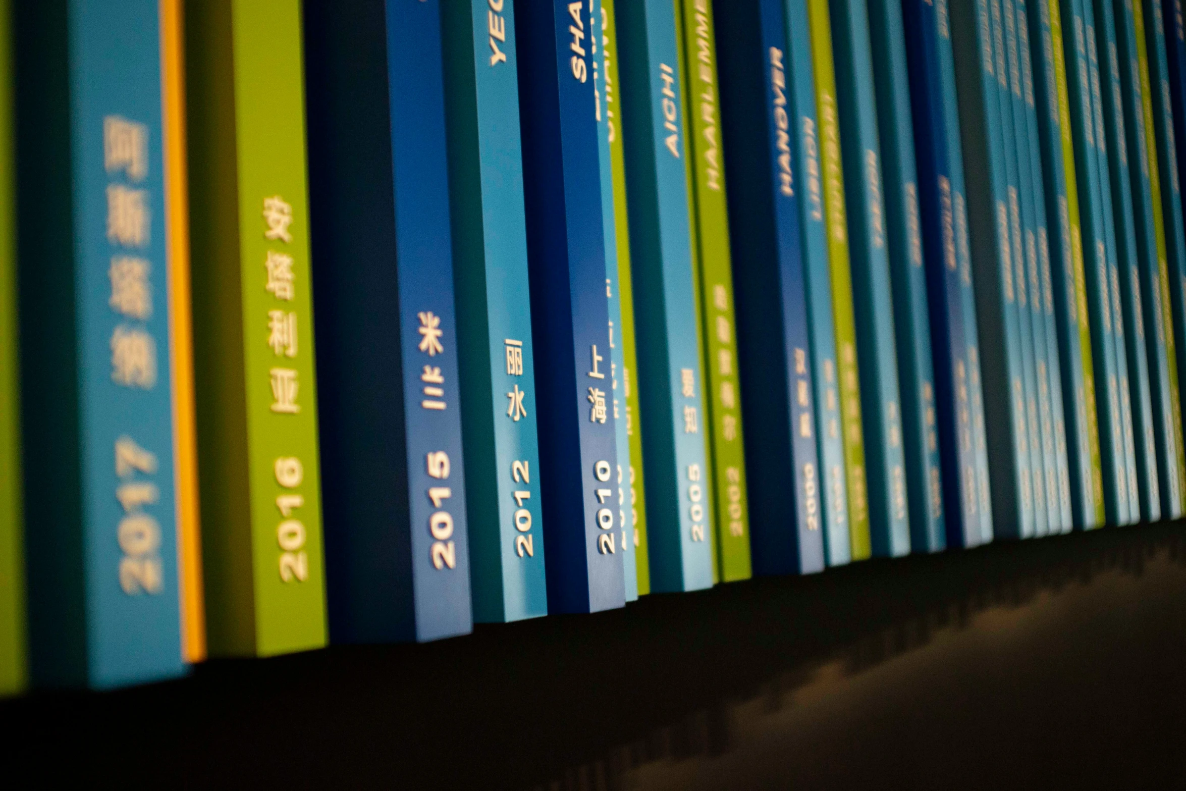 blue and green books lined up against the wall