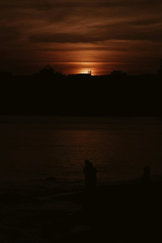 the couple are silhouetted in front of the setting sun