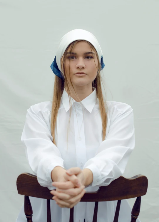 a  sitting in a chair with her hand on her chin