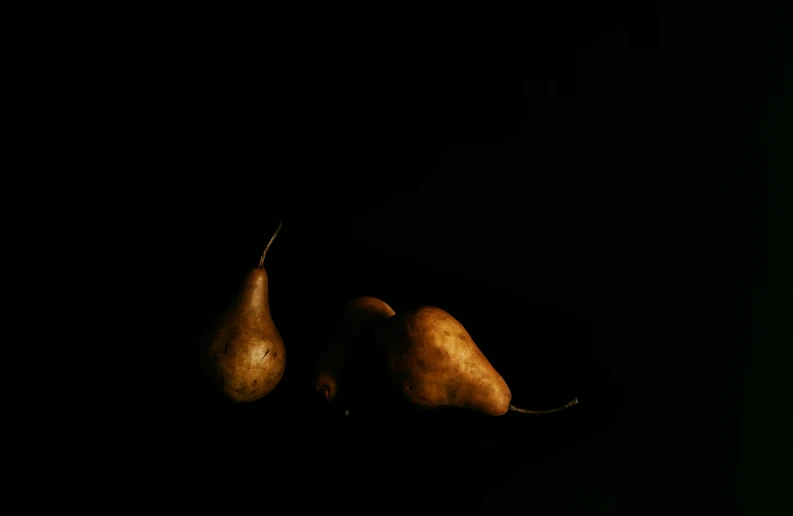 two pears are in the dark, still attached to a string