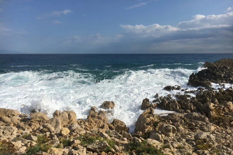 a rock jetty and white foamy waves crashing into the rocks