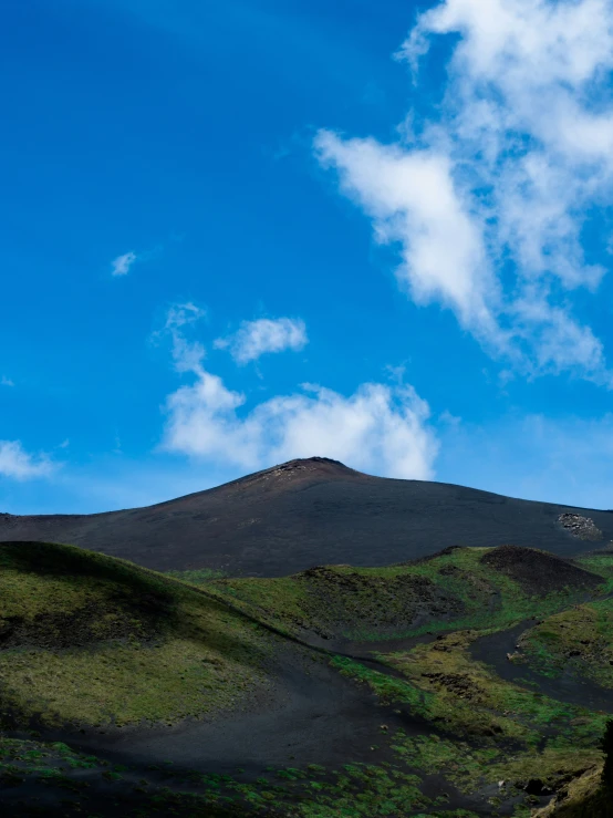 a hill with some clouds and bushes