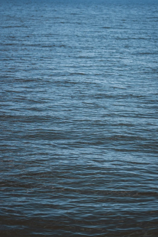 water is reflecting the horizon and a single boat sits on shore