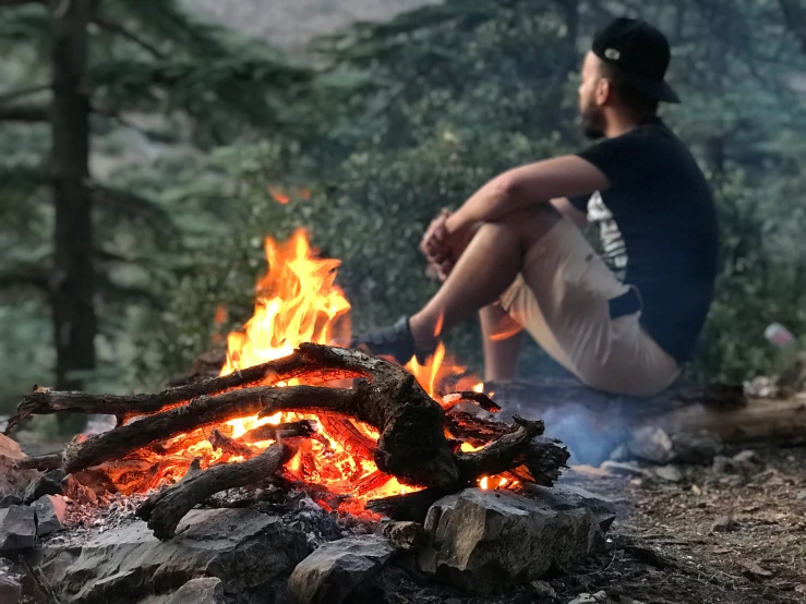 a man sitting next to a fire on the ground