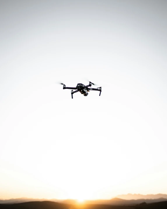 the sun sets over a field with a black and white po of a flying helicopter