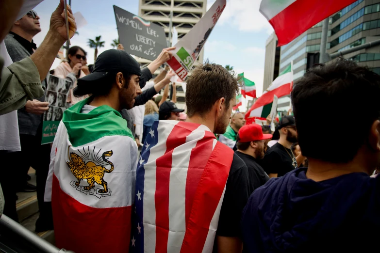 people holding up signs in a crowd near some buildings