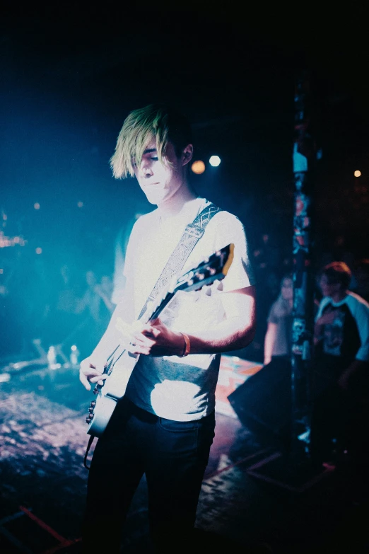 a male in white shirt holding a guitar