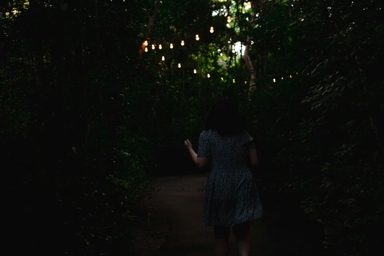 a person walking through some trees and lights