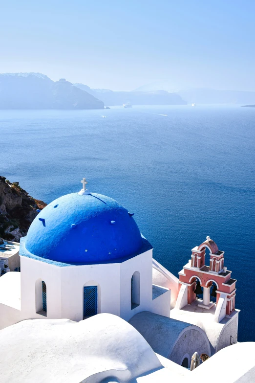 the dome of a white and blue church overlooks a sea landscape