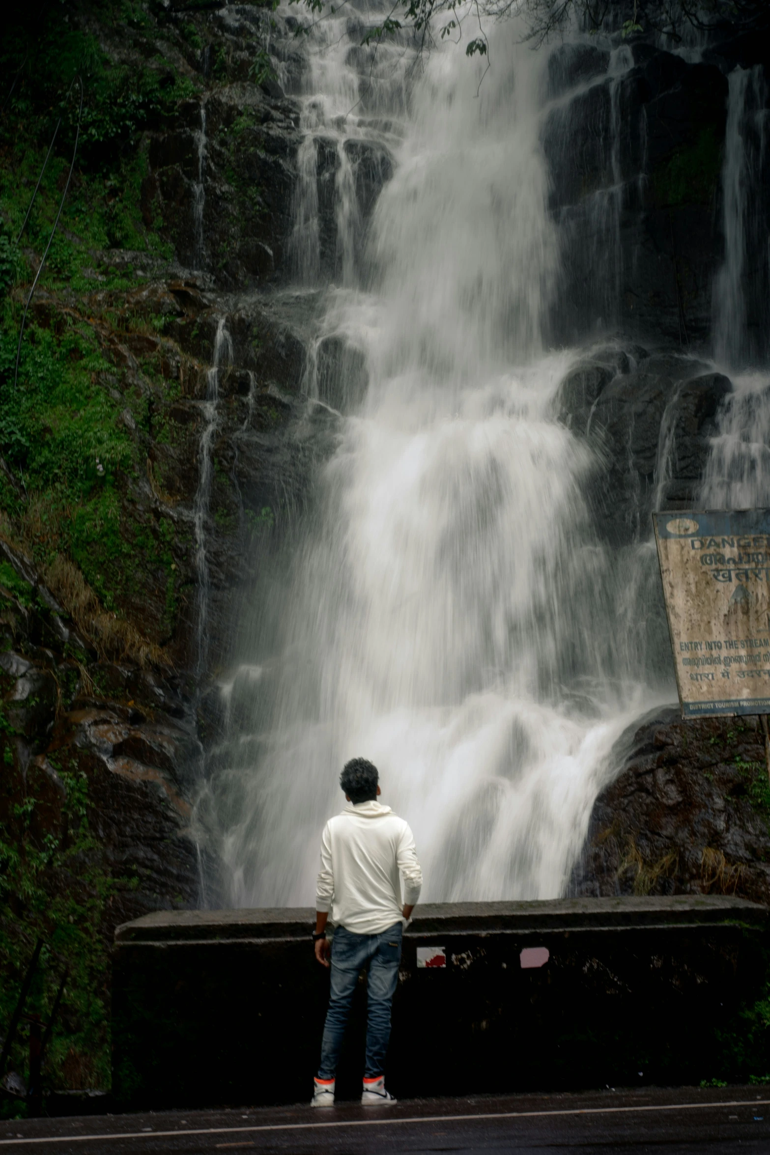 a man looking at a waterfall from near the water
