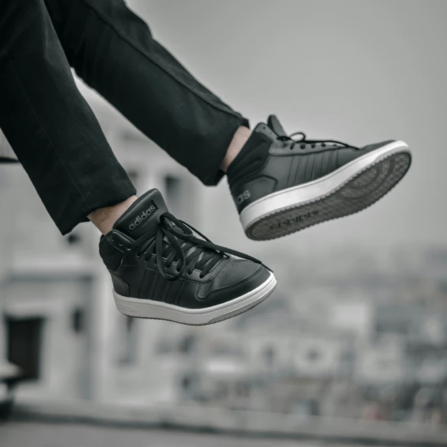 the legs of a person wearing sneakers are dangling from a pair of feet