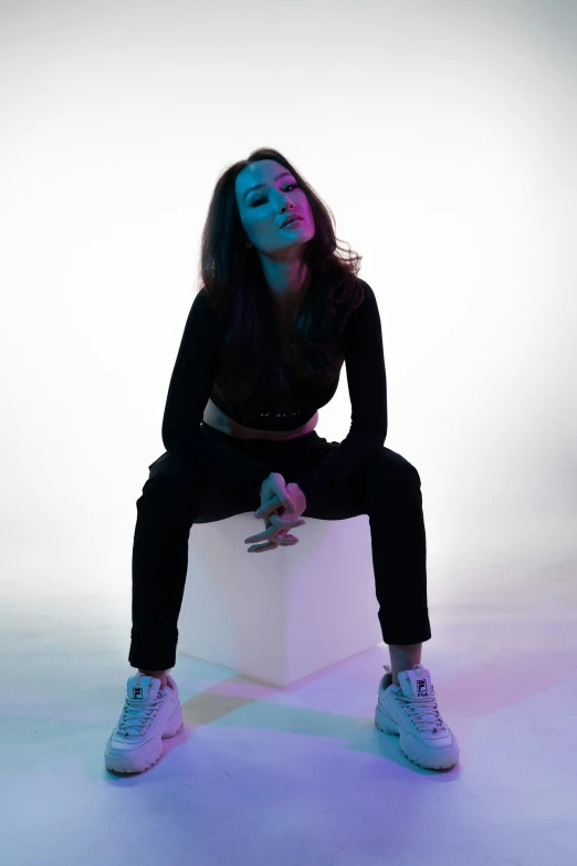 a young woman sitting on top of a white cube