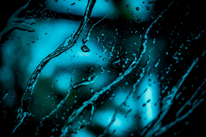 rain water drops off a window on a dark, blurred background