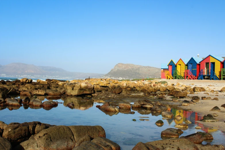 several colorful beach huts along the shore of a beach