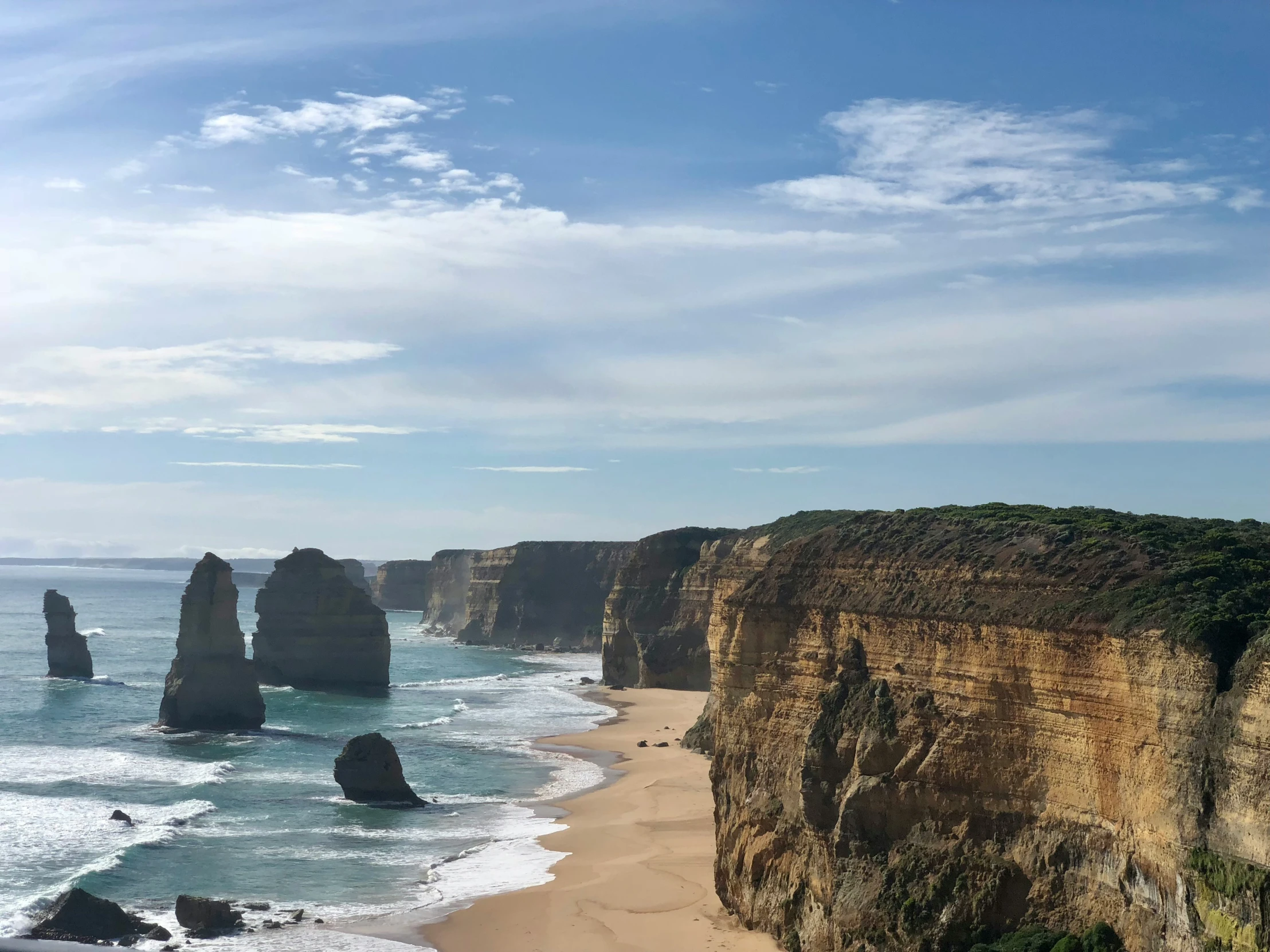 a scenic view of a beach in front of cliffs