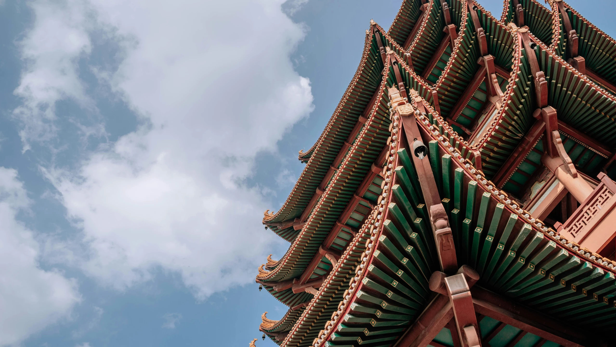 the top of a tall building with green and orange architecture